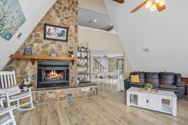 living room with hardwood / wood-style flooring, high vaulted ceiling, ceiling fan, crown molding, and a fireplace