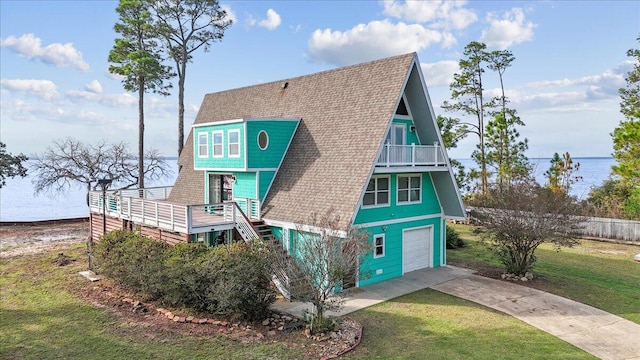 exterior space with a garage, a water view, a lawn, and a balcony