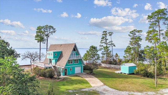 exterior space featuring a storage shed, a garage, a yard, and a water view