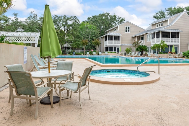 view of pool with a sunroom, a hot tub, and a patio area