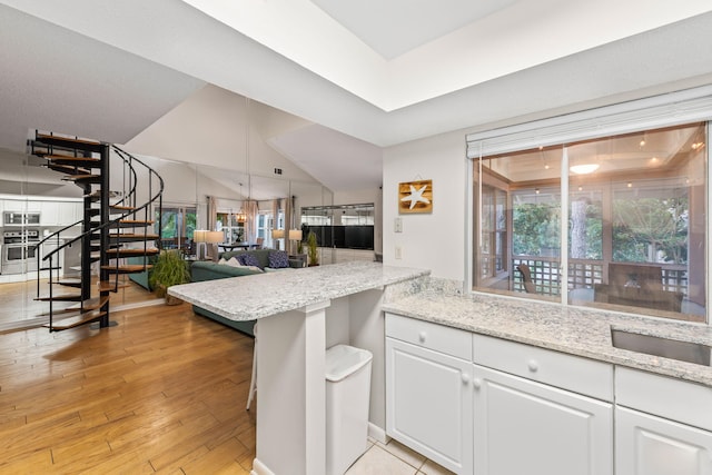 kitchen with white cabinets, a wealth of natural light, light hardwood / wood-style flooring, and kitchen peninsula