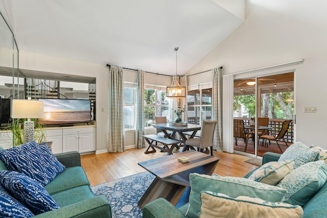 living room with high vaulted ceiling, light wood-type flooring, a chandelier, and plenty of natural light