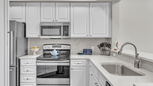 kitchen with white cabinets, appliances with stainless steel finishes, sink, and backsplash