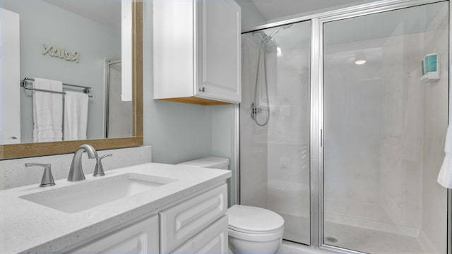 bathroom with a shower with door, vanity, and toilet