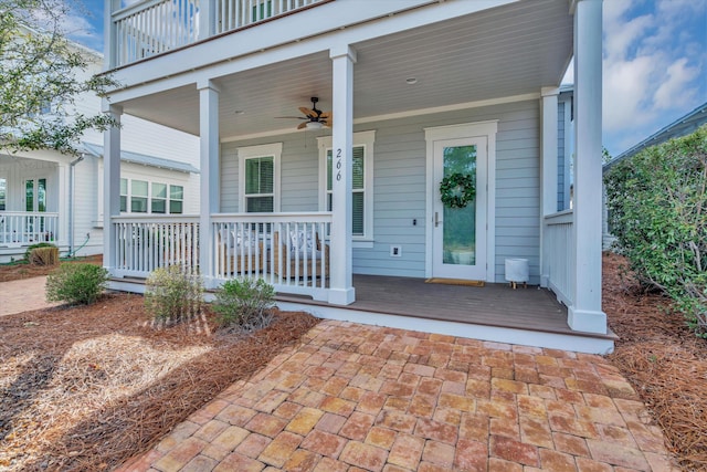 entrance to property with a balcony, covered porch, and ceiling fan