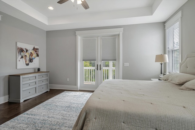 bedroom with dark hardwood / wood-style flooring, a tray ceiling, access to outside, and french doors