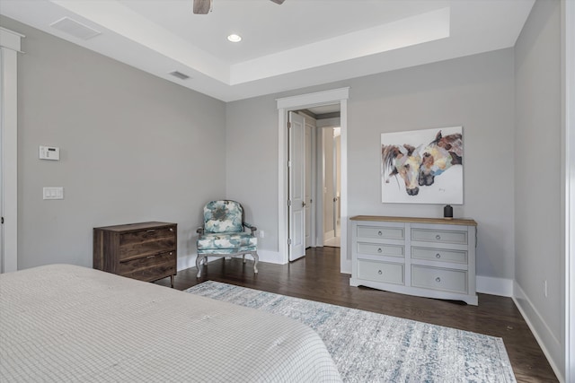 bedroom featuring dark wood-type flooring, ceiling fan, and a raised ceiling