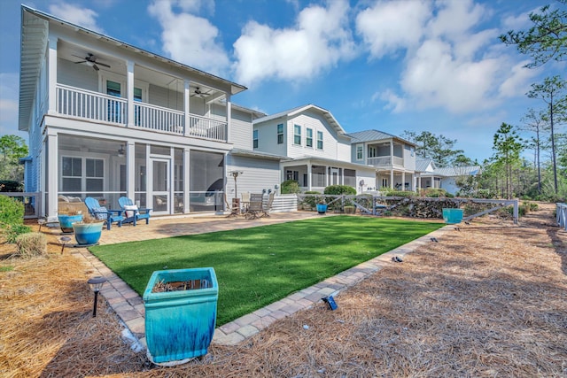 rear view of house with a balcony, a yard, ceiling fan, a sunroom, and a patio area