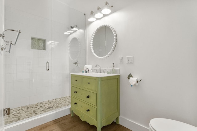 bathroom with hardwood / wood-style floors, vanity, toilet, and a shower with door