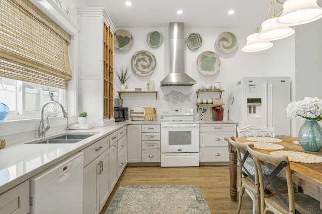 kitchen featuring white cabinetry, sink, wall chimney range hood, light hardwood / wood-style flooring, and white appliances