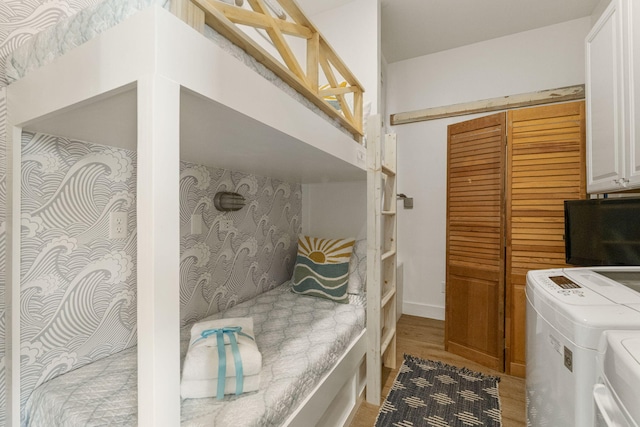 bedroom with washer and clothes dryer, light hardwood / wood-style floors, and a closet