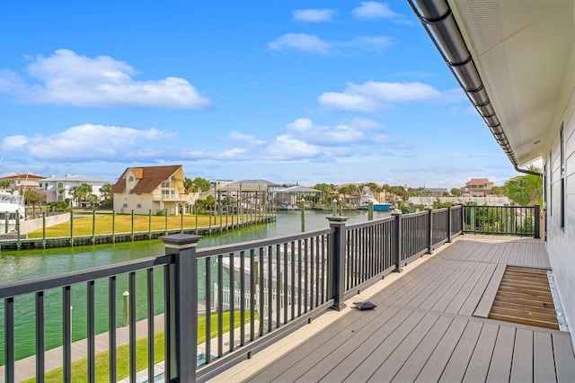 deck featuring a dock, a lawn, and a water view