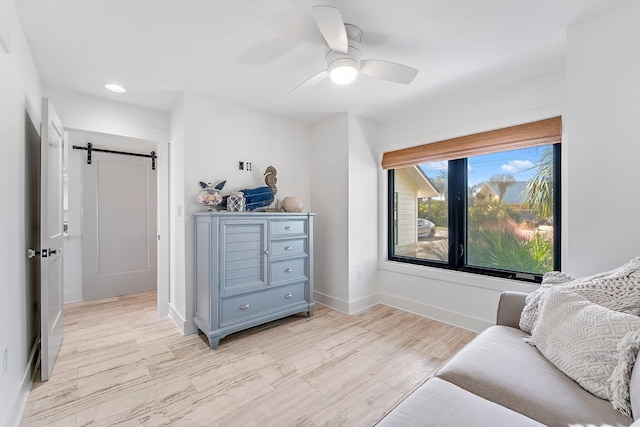 living area featuring ceiling fan and a barn door