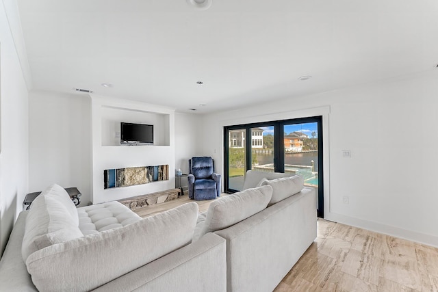 living room featuring light hardwood / wood-style floors, french doors, a fireplace, and crown molding