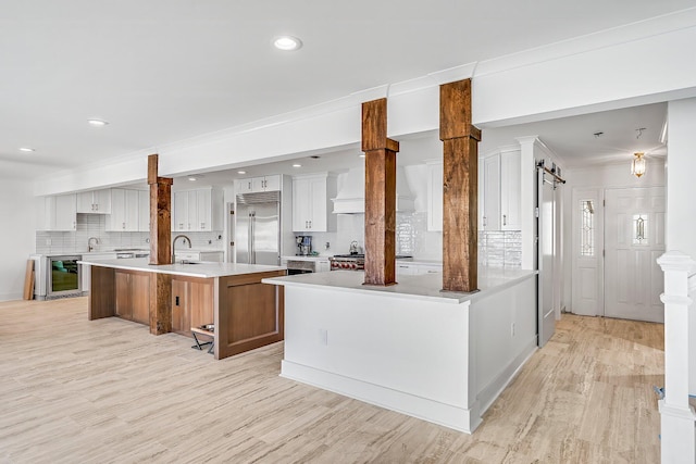 kitchen featuring light hardwood / wood-style flooring, backsplash, a large island, beverage cooler, and stainless steel built in refrigerator