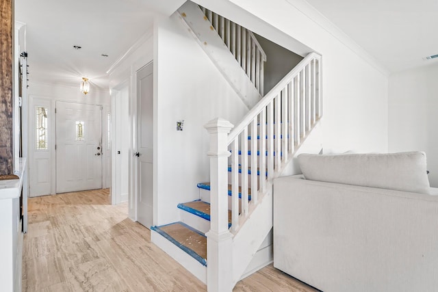 stairway with crown molding and wood-type flooring