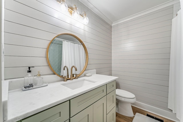 bathroom with vanity, toilet, wooden walls, and hardwood / wood-style floors