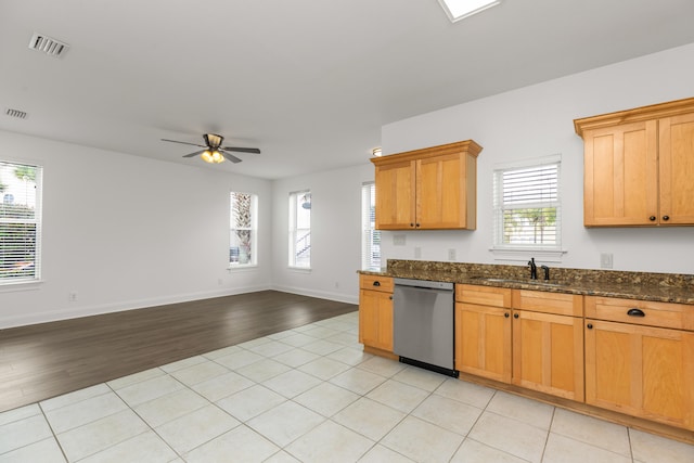 kitchen featuring dark stone countertops, dishwasher, a healthy amount of sunlight, and light wood-type flooring