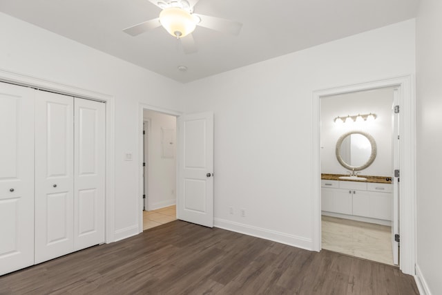 unfurnished bedroom featuring sink, ensuite bath, ceiling fan, dark hardwood / wood-style flooring, and a closet