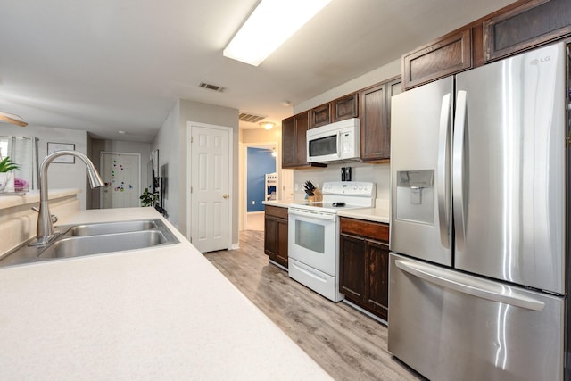 kitchen with white appliances, light hardwood / wood-style flooring, dark brown cabinets, and sink