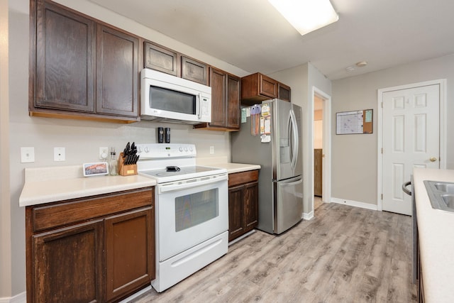 kitchen with white appliances, light hardwood / wood-style floors, dark brown cabinets, and sink