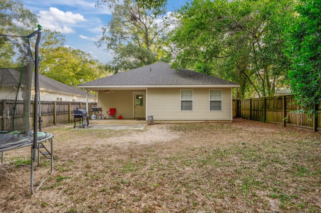 back of property with a yard, a trampoline, and a patio