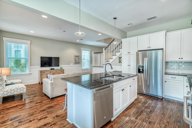 kitchen featuring appliances with stainless steel finishes, sink, white cabinetry, dark wood-type flooring, and a center island with sink