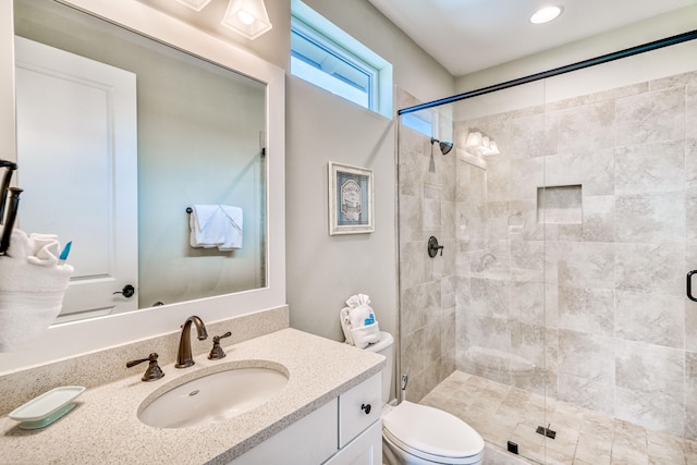 bathroom featuring toilet, an enclosed shower, and vanity