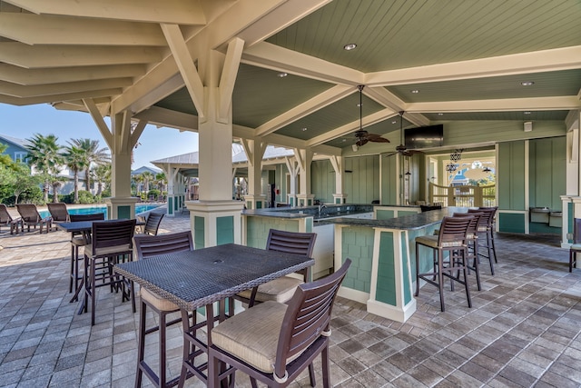 view of patio / terrace with an outdoor bar, ceiling fan, exterior kitchen, and a pool