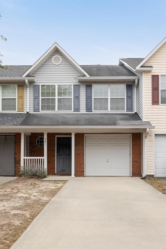 multi unit property featuring driveway, covered porch, a garage, and brick siding