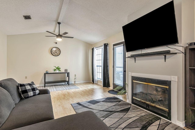 living room with ceiling fan, vaulted ceiling, and light hardwood / wood-style floors