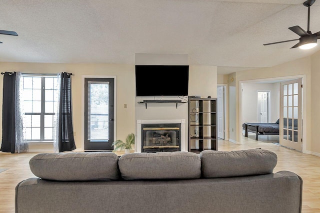 living room featuring ceiling fan, a textured ceiling, and light hardwood / wood-style floors