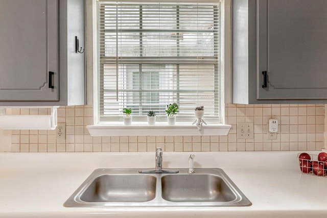 kitchen featuring gray cabinets, backsplash, and sink