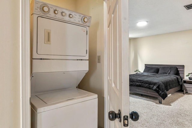 laundry room featuring stacked washer and clothes dryer, a textured ceiling, and carpet flooring