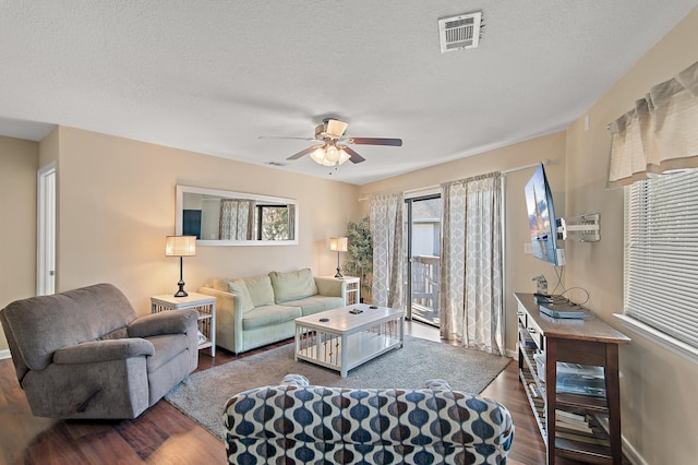 living room featuring a textured ceiling, ceiling fan, and dark hardwood / wood-style flooring