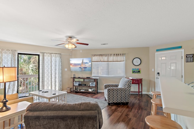 living room featuring ceiling fan, a textured ceiling, and dark hardwood / wood-style flooring