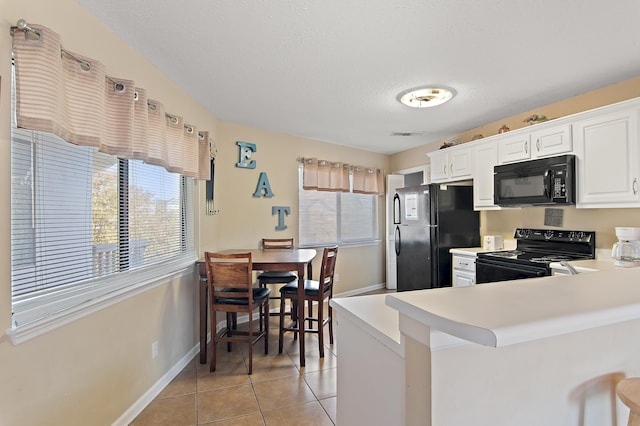 kitchen featuring black appliances, light tile patterned flooring, a textured ceiling, kitchen peninsula, and white cabinetry