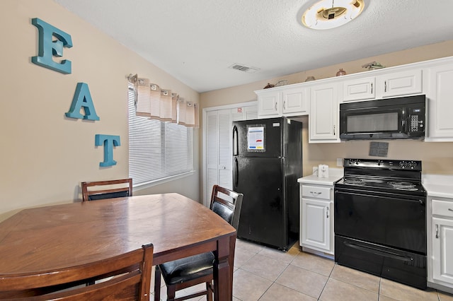 kitchen featuring lofted ceiling, black appliances, light tile patterned flooring, white cabinets, and a textured ceiling