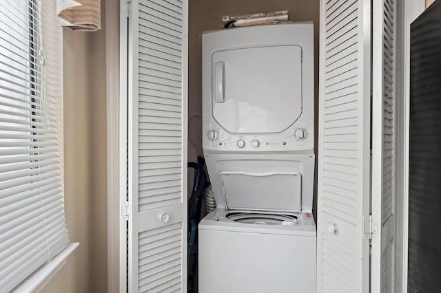 clothes washing area with stacked washing maching and dryer