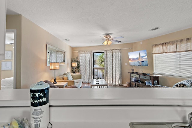 living room with a textured ceiling and ceiling fan