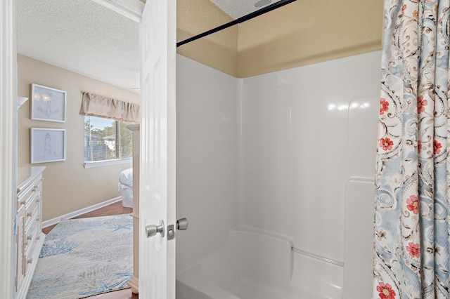 bathroom with hardwood / wood-style floors, a textured ceiling, and shower / bathtub combination with curtain