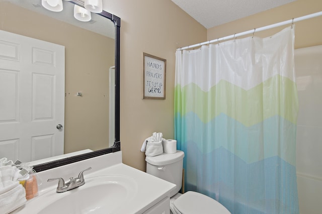 bathroom with toilet, a textured ceiling, walk in shower, and vanity