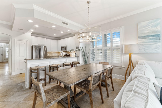 tiled dining room with sink, a chandelier, and ornamental molding