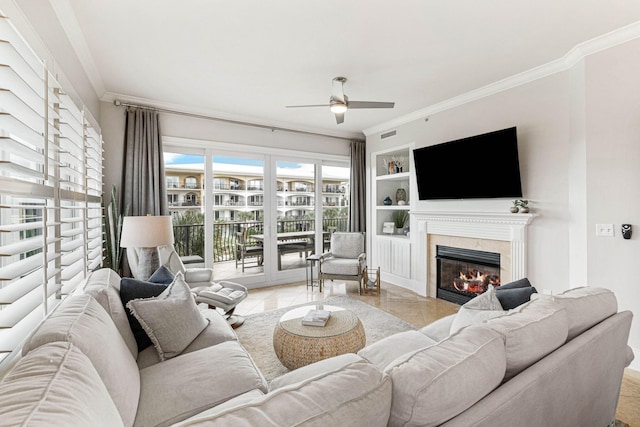 tiled living room featuring ceiling fan, built in features, crown molding, and a tile fireplace