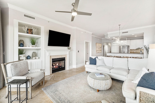 living room featuring built in features, ceiling fan, and crown molding