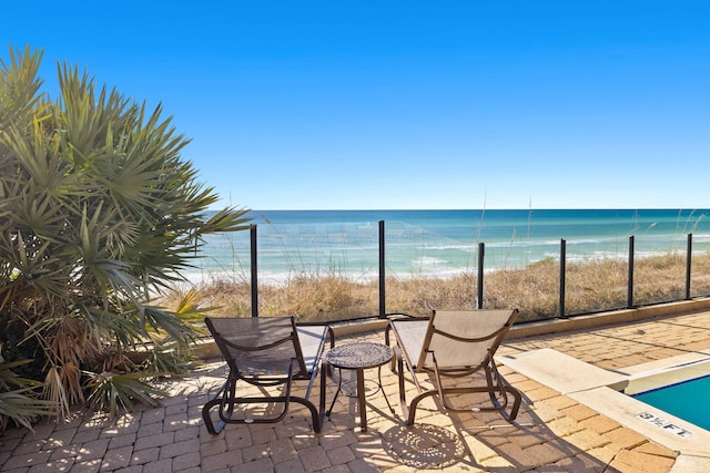 view of patio / terrace with a water view and a beach view