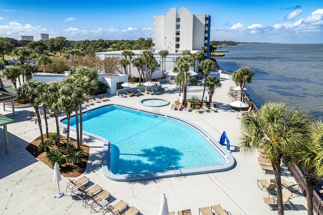 view of pool with a water view, a patio, and a community hot tub