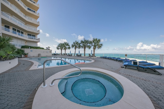 view of swimming pool featuring a patio, a water view, and a community hot tub