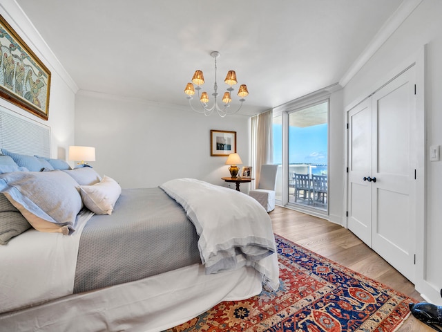 bedroom featuring access to exterior, light hardwood / wood-style floors, a chandelier, and crown molding