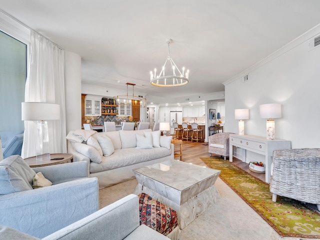 living room with ornamental molding, light wood-type flooring, and a chandelier